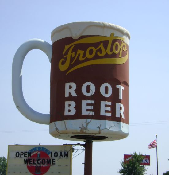 A roadside sign in the shape of a mug that advertises Frostop Root Beer 