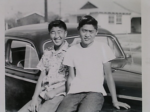 A picture from the exhibit of two Japanese boys leaning against a 50s car.