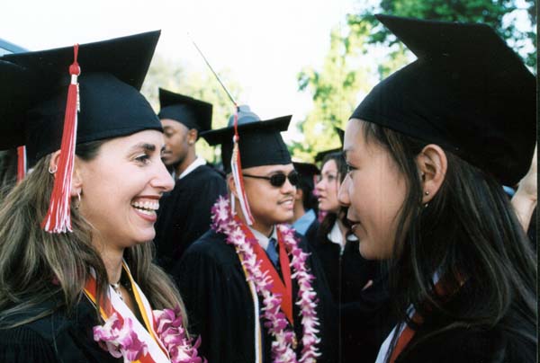 Two women graduates greeting