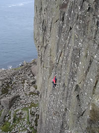 Mountain climber clings precariously to a  cliff