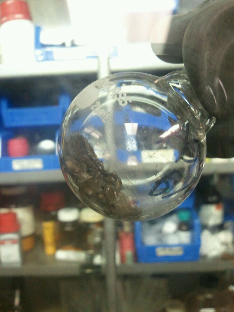 A photograph of brown norbornene polymer in a round-bottomed flask produced from using a ruthenium-based catalyst.
