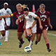 CSUN soccer player dribbling the ball against two LMU defenders.