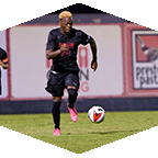 A men's soccer player dribbles the ball.