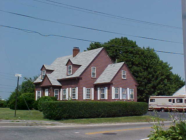 This is a Cape Cod house. It is common in New England, and other parts of the Yankee cultural region. It is a story and a half, with a central front door and a central chimney. Rooms are arranged around the chimney, as is the stairs to the upper floor. The roof is often steep and the gables are always on the end. Generally constructed of wood, they often feature rooms additions in order to accommodate the needs of most contemporary families.