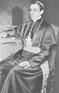 photo, Cardinal Pacelli seated in a chair next to a table