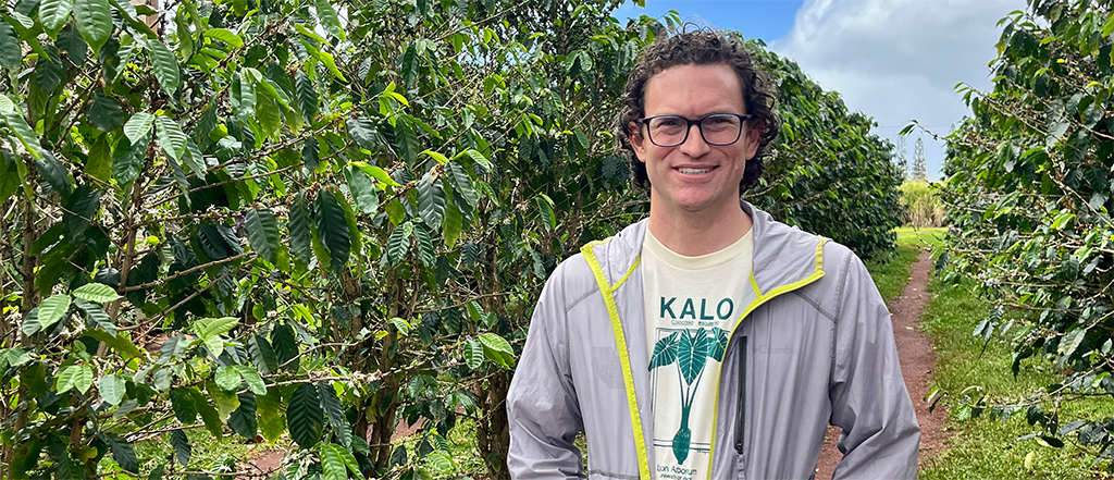 Luke Drake standing in a row of coffee plants