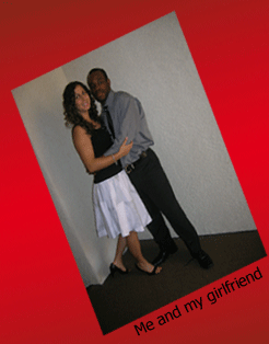 My girlfriend and I standing in a hallway after church posing. She is wearing a shirt with a white skirt and I have on black pants with a gray button up shirt.