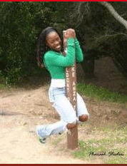 My lovely sister at one of her photoshots hanging on a little pole with a big smile on her face. She is wearing blue jeans with a green shirt.