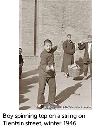 Boy spinning top on a string on Tientsin street, winter 1946 