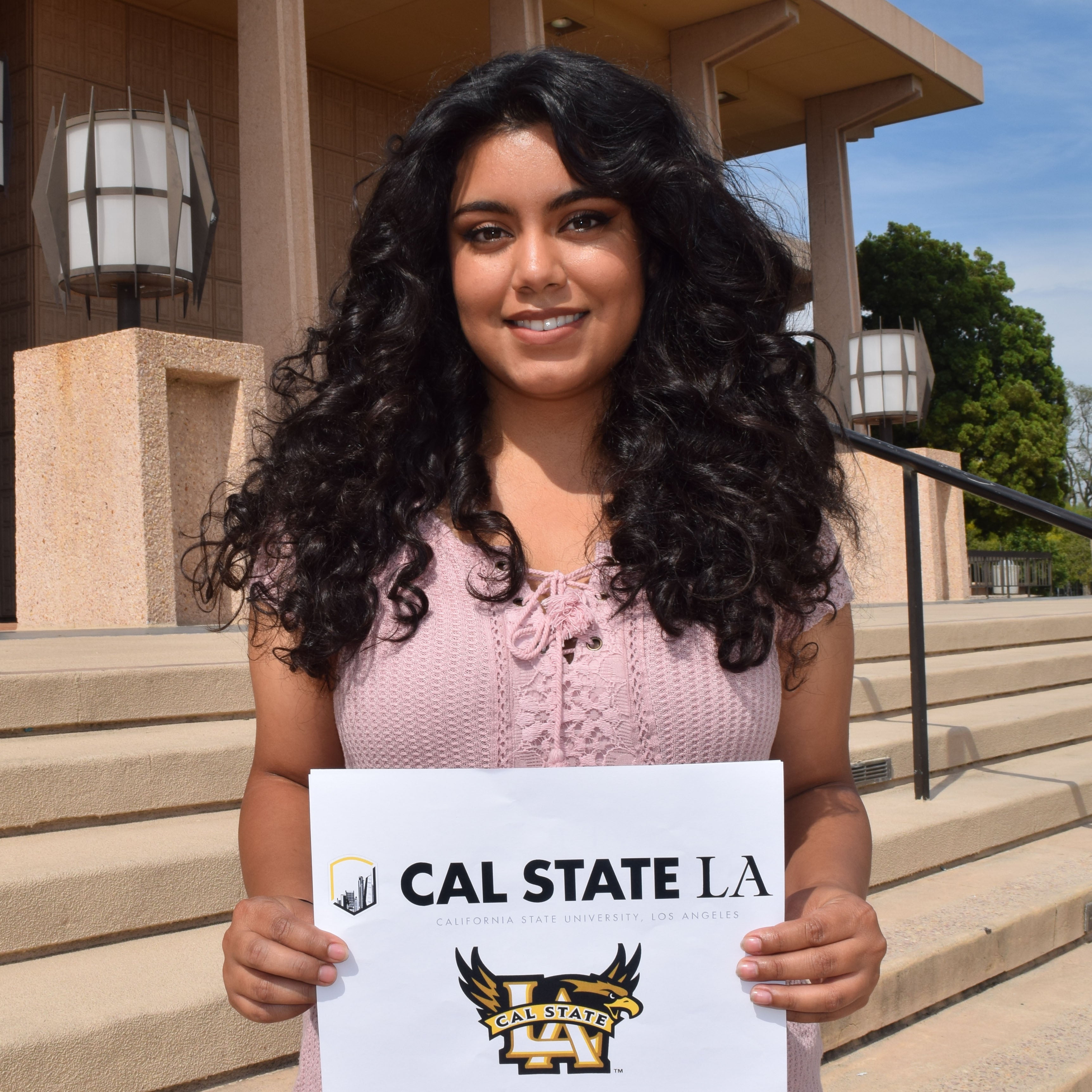 Adriana holds sign showing her graduate school choice Cal State LA