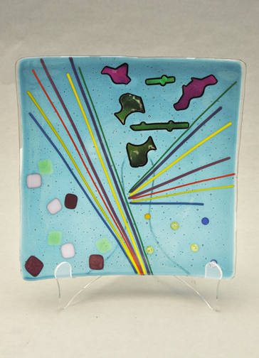 Abstract design fused glass plate 10 inches by ten inches with blue background and colorful lines and shapes