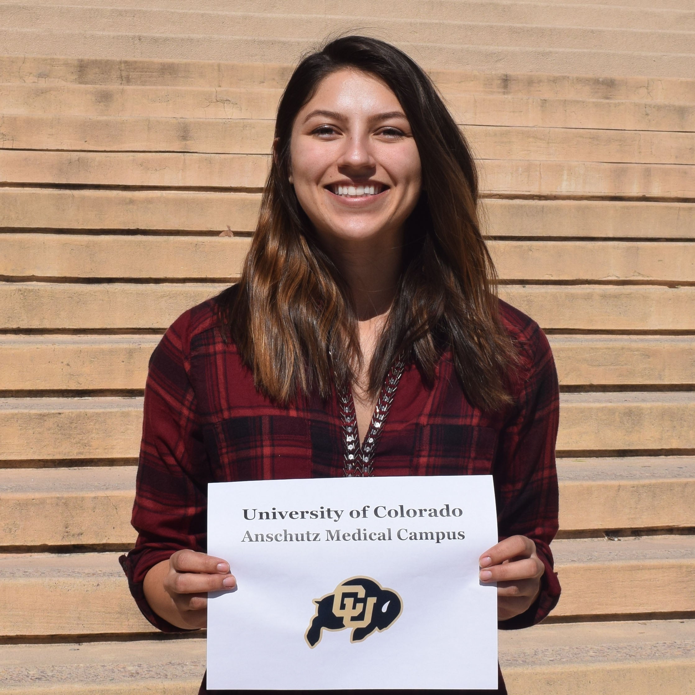 Ashley holds sign showing her graduate school choice the University of Colorado, Denver
