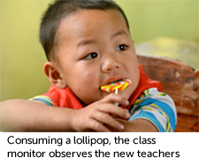 Consuming a lollipop, the class monitor observes the new teachers