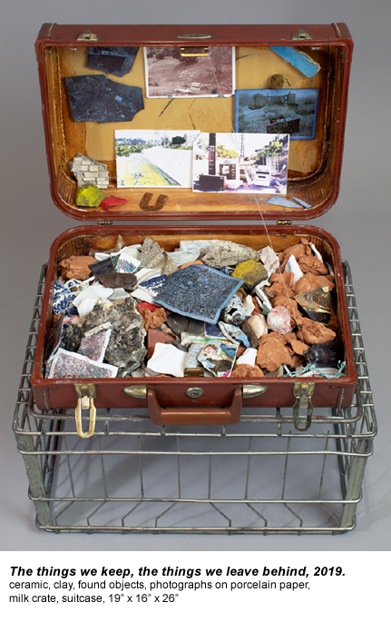 The things we keep, the things we leave behind, 2019. ceramic, clay, found objects, photographs on porcelain paper,  milk crate, suitcase, 19” x 16” x 26”