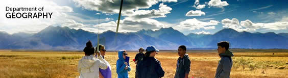 Geography students out in the field with mountains and clouds.