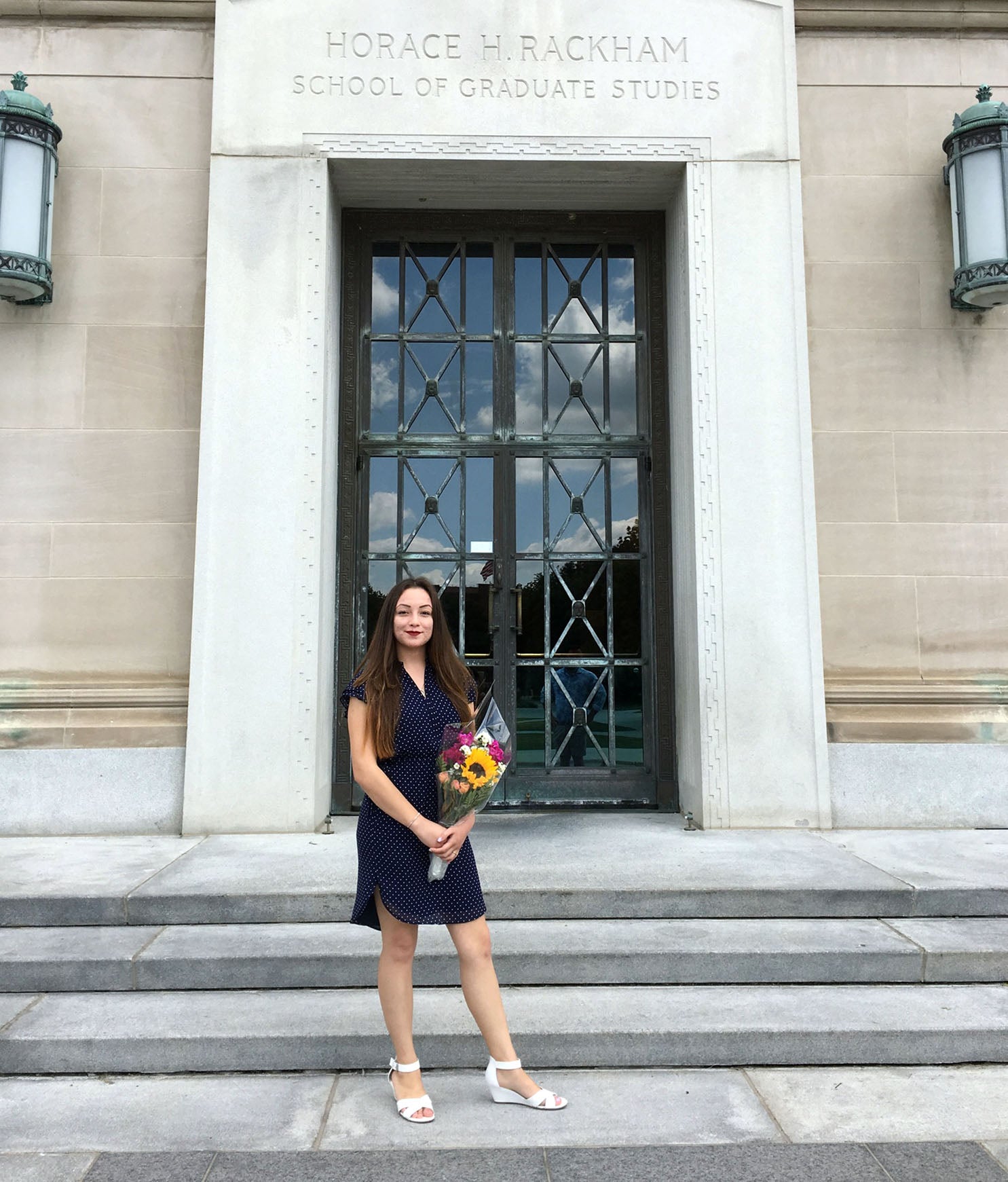 Jacqueline poses with flowers outside the Horace H. Rackham School of Graduate Studies