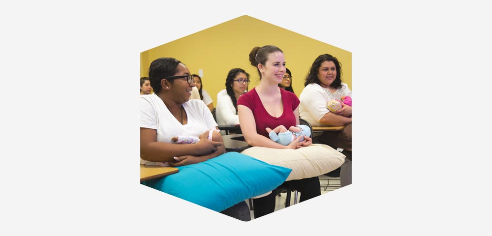 Students performing lactation excercises with dolls.