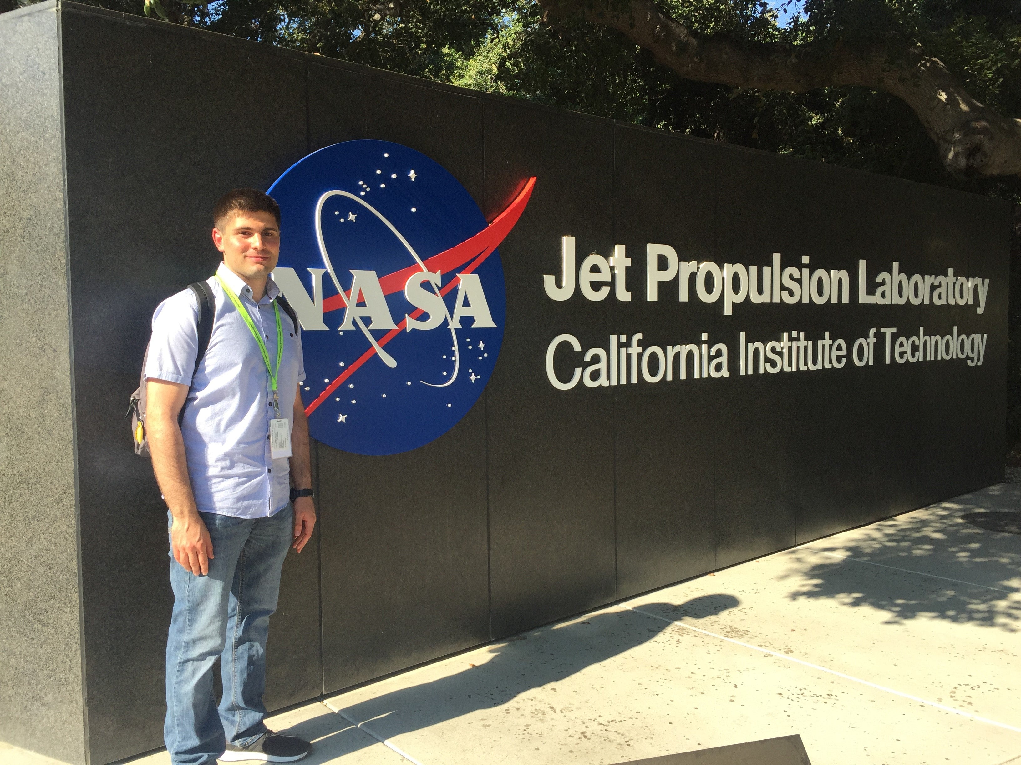 Ohannes smiles next to the NASA Jet Propulsion Labratory sign at the California Institute of Technology campus