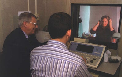 professor watches as student learns how to administer a hearing test
