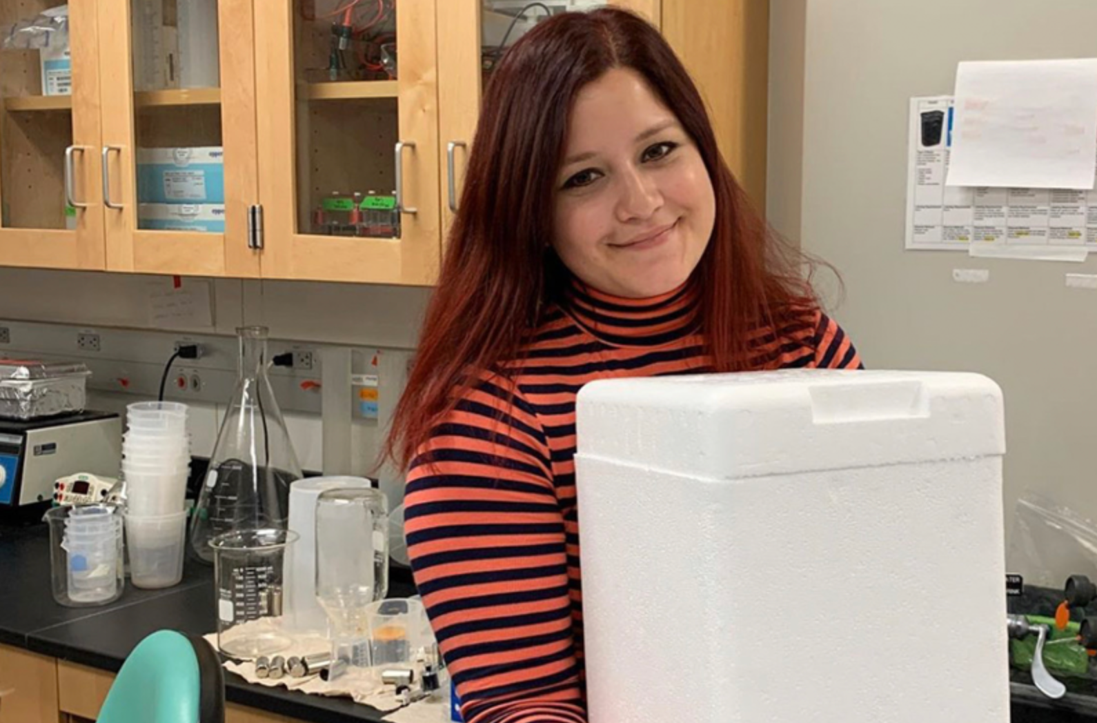 Yolanda Salgado Vasquez carrying a box of viles in a lab