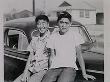 Two asian american boys sitting on a car
