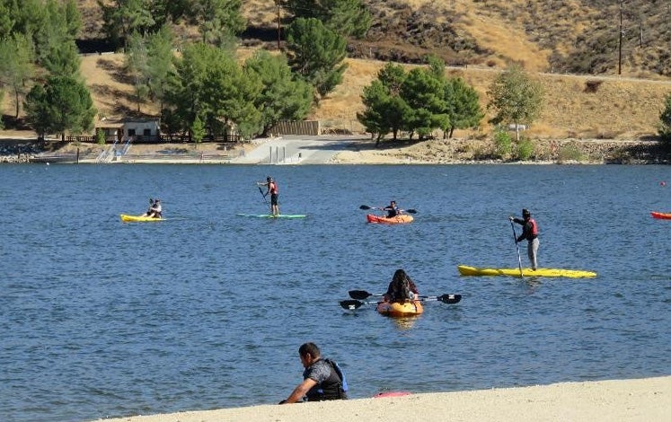 people having fun paddling kayaks and paddle boards on the lake