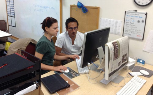 A man and a woman working at a computer. 