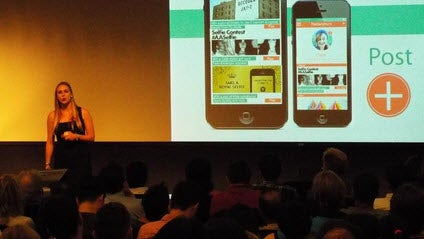 A female student is shown presenting an app idea to the audience.