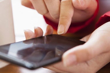 A close-up of a person using a smartphone (PC Magazine).