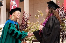 President Dianne F. Harrison shaking a student's hand at commencement.
