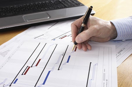 Close-up of a man with a pen working on plans.