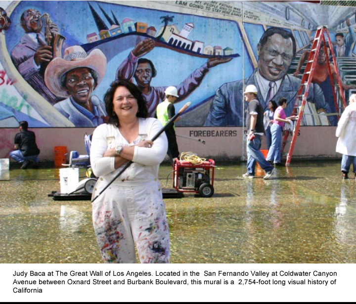 Judy Baca standing in front of mural