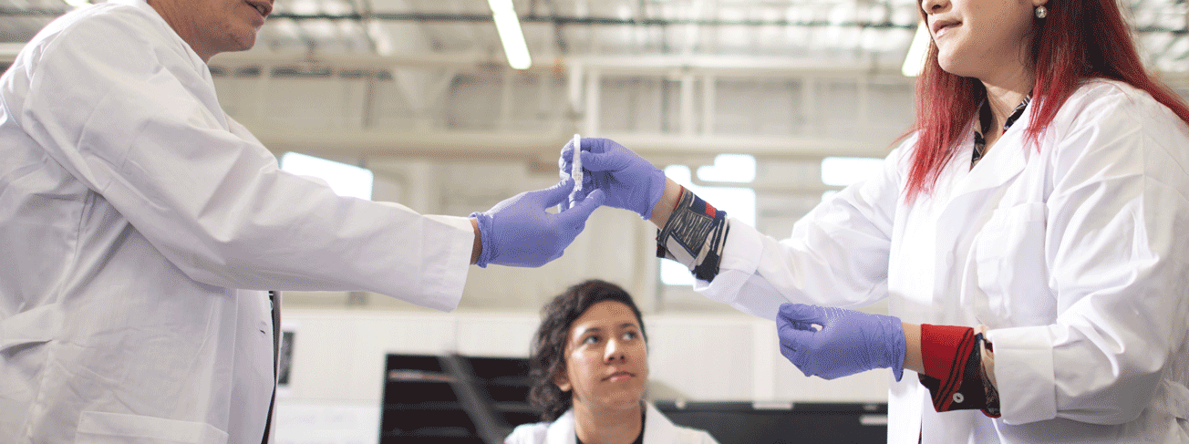 two research assistants in lab coats passing a vile