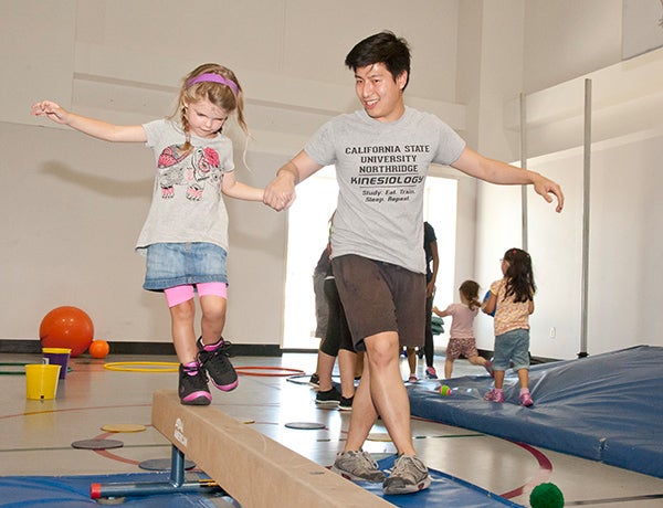 csun student helps child participant in sensory motor program in kinesiology