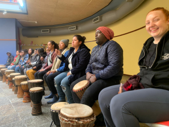 A group of trip participants seated in front of djembe drums
