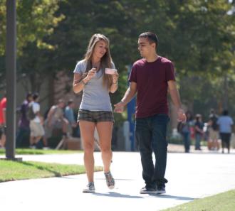 Students walk while looking at smartphone