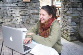 A young woman sitting outside using a laptop computer. 