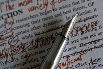 A pen against newsprint with edits. 