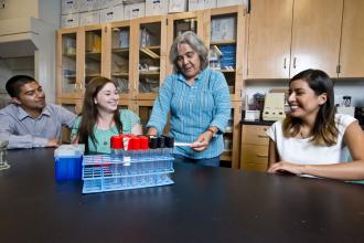 Dr. Maria Elena Zavala with three students in lab.