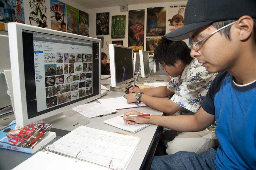 A CSUN Department of Art student researches and sketches images of dinosaurs for a class assignment.
