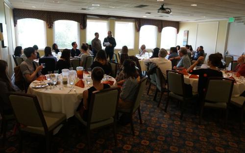 Dr. David Boyns and Doug Kaback presenting to a dining hall room filled with Institute partners.