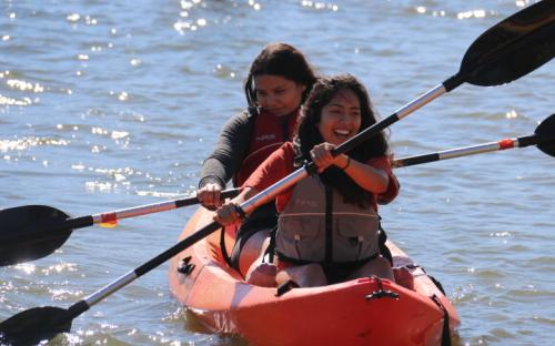 Scholars Diana and Melisa sailing through the lake on a canoe.