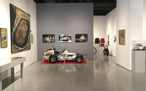  install image of the entry way of gallery as you enter the show.  The left wall has a large blow up of the Ascot track.  Strait ahead is the Number 98 midget race car. 