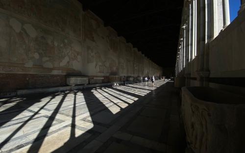 Shadowed colonnade along frescoed hallway – Pisa, Italy 