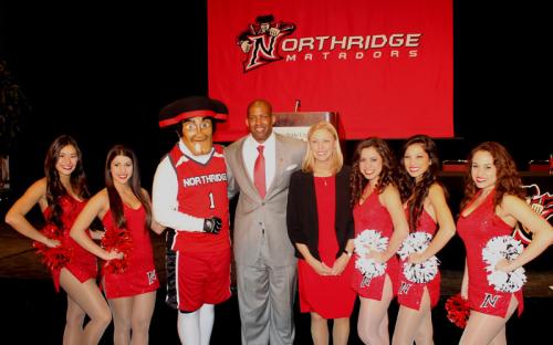 President Harrison poses with CSUN’s Director of Intercollegiate Athletics Brandon E. Martin and the Matador cheerleaders.