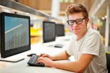 Young man smiling while typing on a computer.
