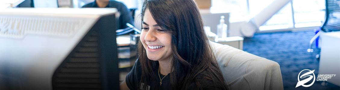 Image of smiling USU student assistant employee sitting at a computer
