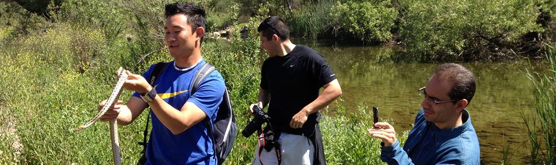 Science education students holding a snake near a lake