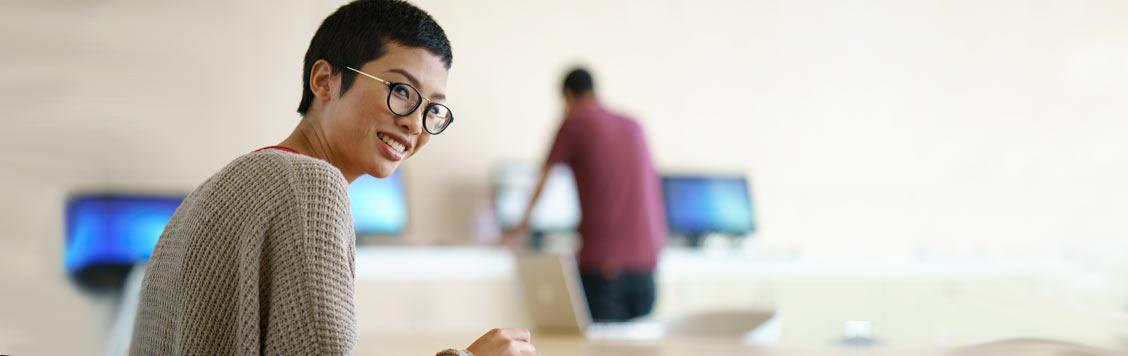 Smiling female student at desk turning to camera.