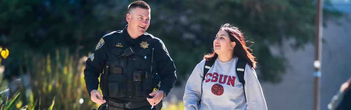 A male officer and female student walking on campus.